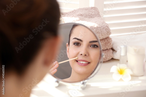 Young woman removing facial...