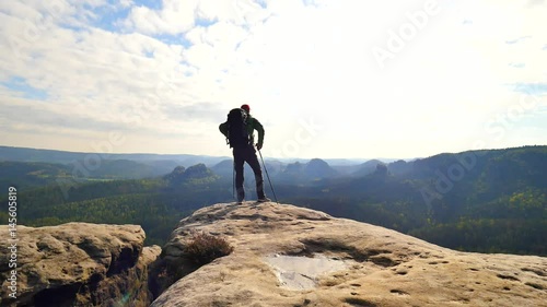 Silhouette of young tourist guide looking in paper  map in nature while hiking.  Man hiker with heavy backpack. 