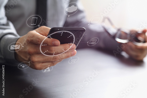Fototapeta Naklejka Na Ścianę i Meble -  close up of businessman working with mobile phone and eyeglass on wooden desk in modern office