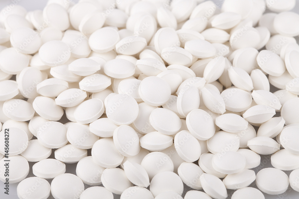 White vitamin D pills on a white surface. Vitamins isolated on white background. White vitamin D pills on a white surface. Vitamins isolated on white background.