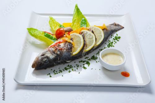 Grilled whole fish decorated with leaves of lettuce and cherry tomato, served with garlic sauce. Fried whole fish