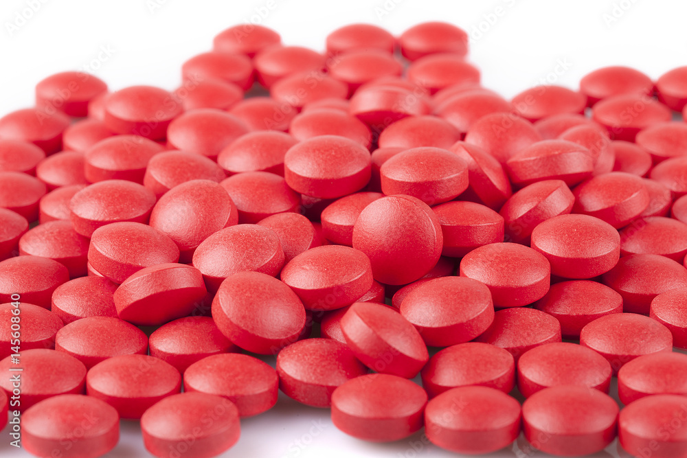 Red pills on a white surface. Red pills isolated on white background. Red pills on a white surface. Red pills isolated on white background.