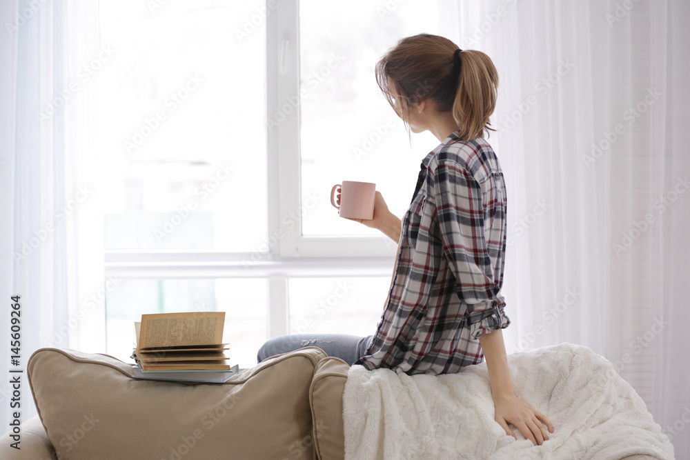 Beautiful young woman with cup of tea and books resting at home Beautiful young woman with cup of tea and books resting at home