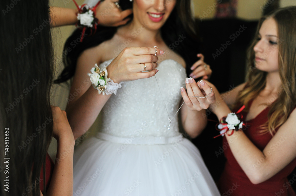 Happy cheerful brunette bride wearing at her room with two bridesmaids on red dress.