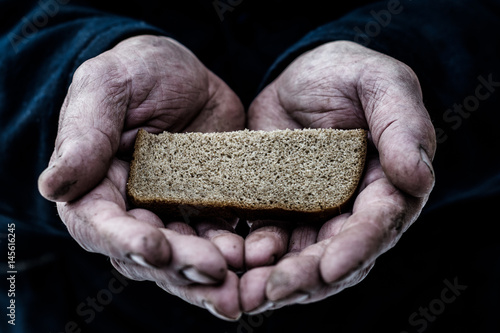 Dirty hands of a man clamped a piece of bread. 