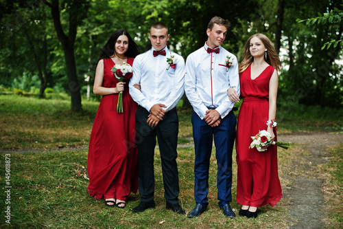 Bridesmaids at red dresses with groomsman or best man at wedding.