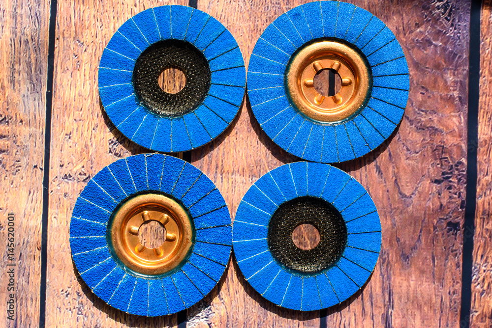 Grinder discs. A pile of color flap abrasive industrial disks on wood background texture. Great for grinding, metal finishing, sanding steel or inox. Grinder discs - professional equipment Grinder discs. A pile of color flap abrasive industrial disks on wood background texture. Great for grinding, metal finishing, sanding steel or inox. Grinder discs - professional equipment