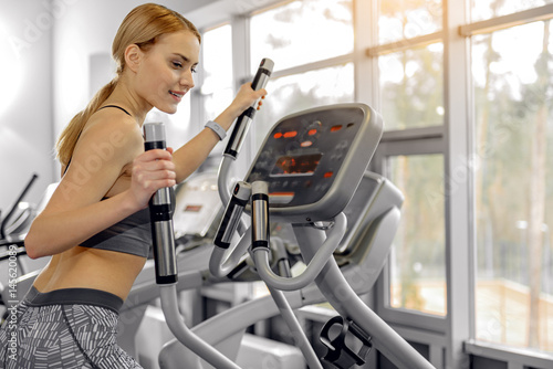 Happy woman running on cross trainer