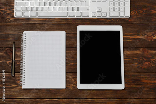 Office workplace with text space. Top view of office dark desk table with laptop, phone, tablet, notebook, and coffee cup. Top view with copy space Modern office workplace.