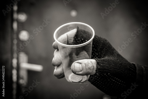 In the man's hand squeezed the plastic Cup. In a plastic Cup are different coins.
