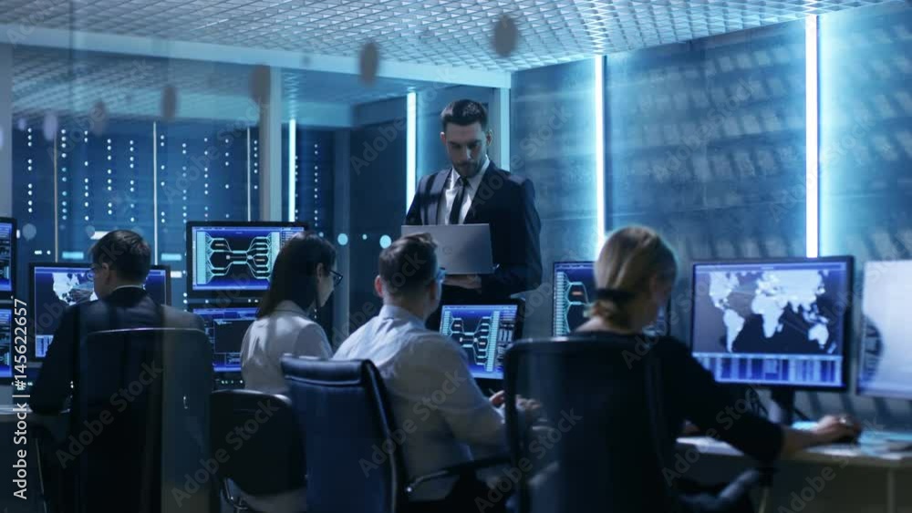 Professional IT Engineers Working in System Control Center Full of Monitors and Servers. Possibly Government Agency Conducts Investigation. Shot on RED EPIC-W 8K Helium Cinema Camera. Professional IT Engineers Working in System Control Center Full of Monitors and Servers. Possibly Government Agency Conducts Investigation. Shot on RED EPIC-W 8K Helium Cinema Camera.