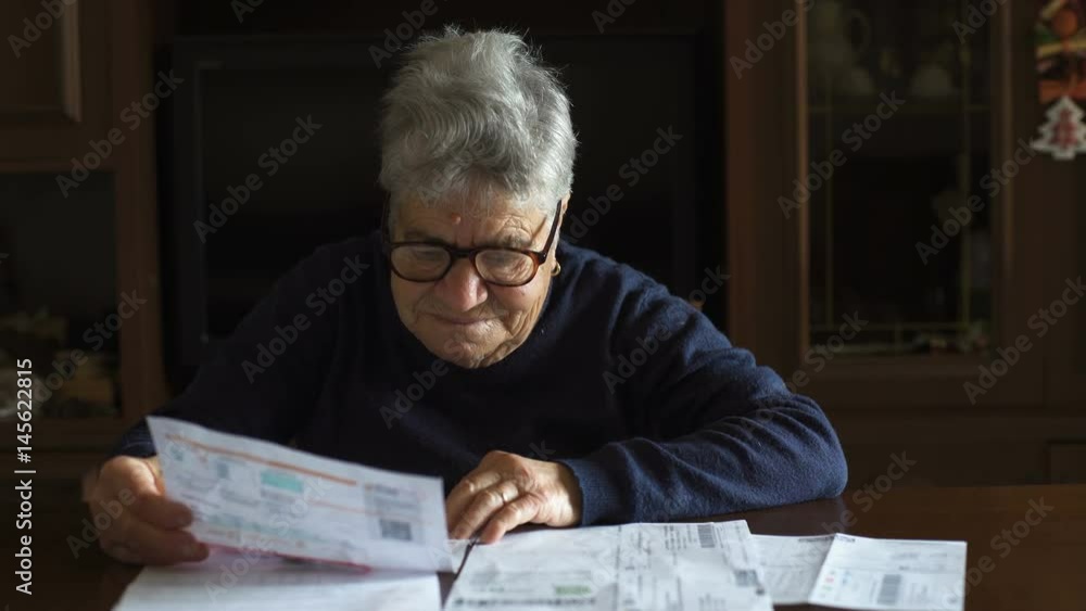 Old retired woman checks bills and despairs Old retired woman checks bills and despairs