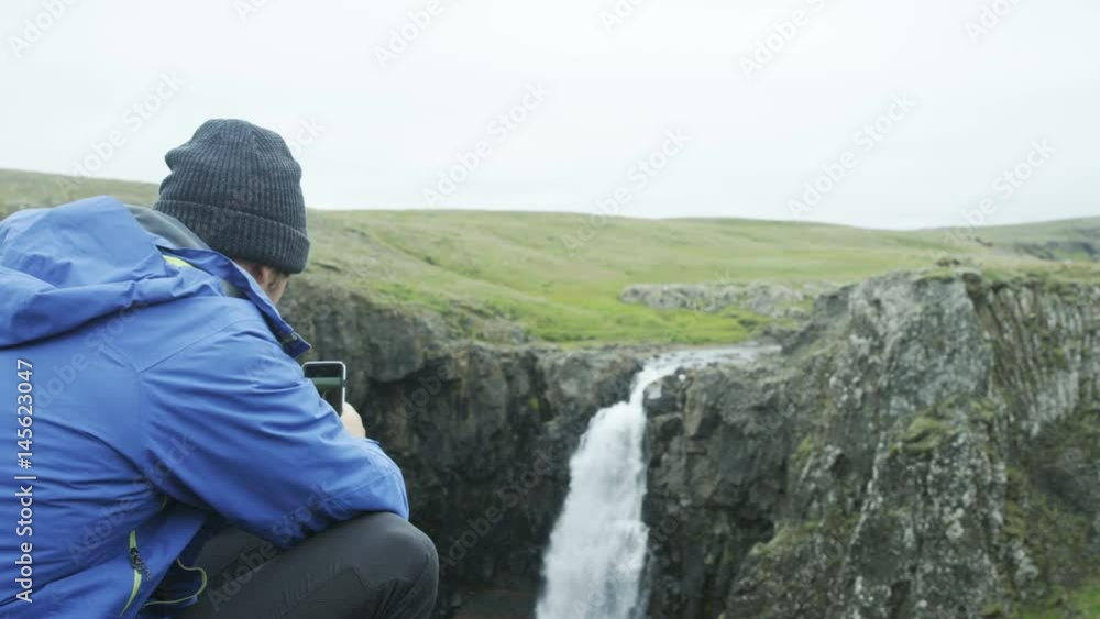 man taking photo of waterfall with his cell phone man taking photo of waterfall with his cell phone