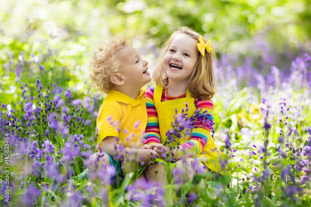 Kids playing in blooming garden with bluebell flowers Kids playing in blooming garden with bluebell flowers