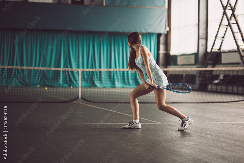 Full body portrait of young girl tennis player in action in a tennis court indoor Full body portrait of young girl tennis player in action in a tennis court indoor