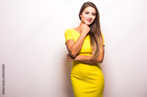 Woman fashion model standing in yellow dress against gray background