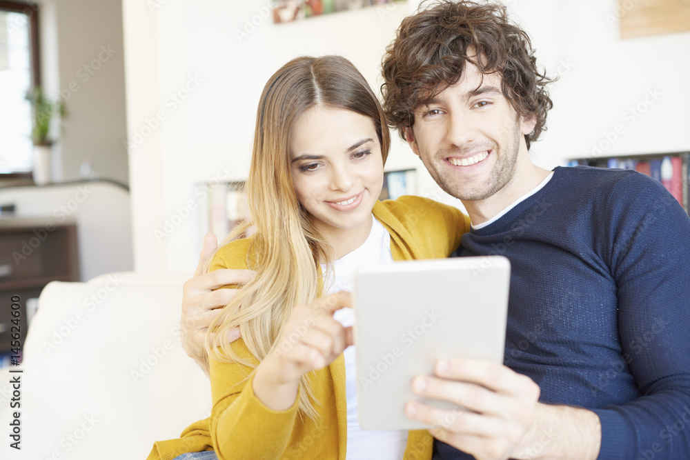 Enjoy browsing on the internet. Portrait of a lovely young couple sitting on the couch with their digital tablet at home and browsing on the internet. Enjoy browsing on the internet. Portrait of a lovely young couple sitting on the couch with their digital tablet at home and browsing on the internet.