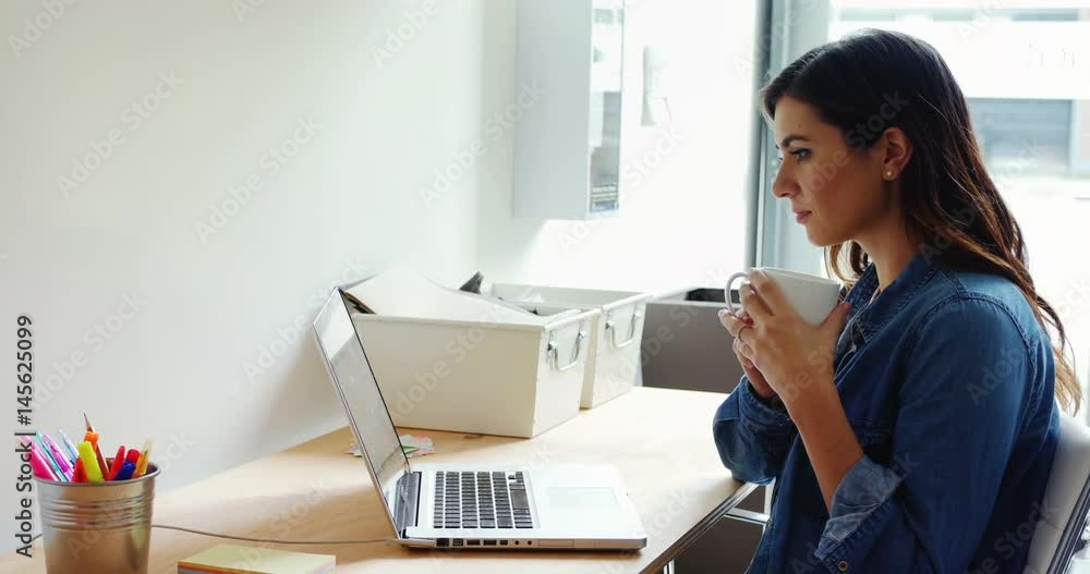 Female executive using laptop white having coffee