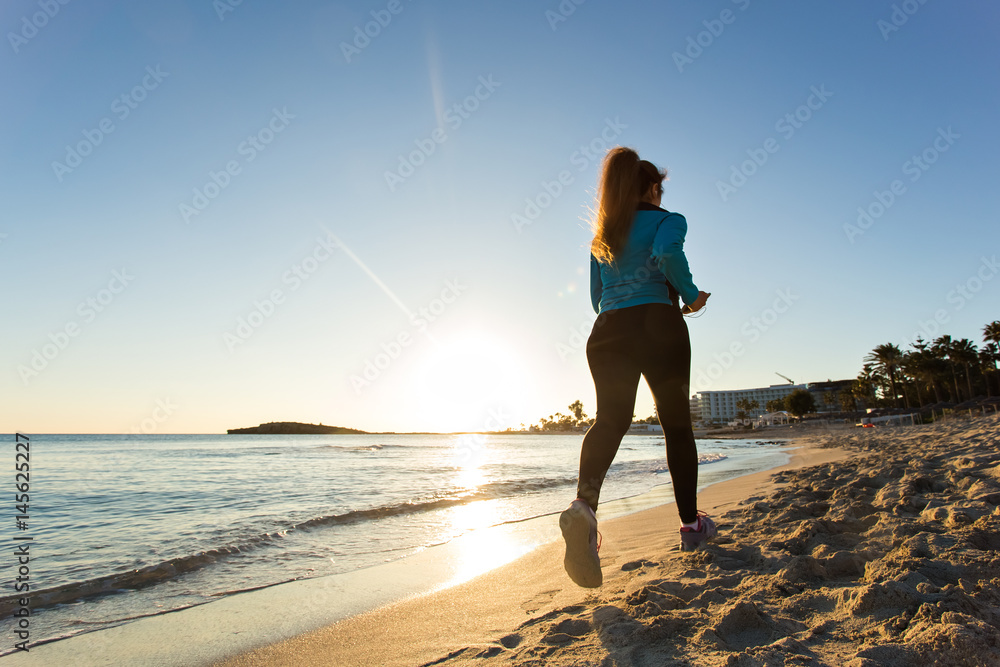 Fitness Woman Running by the Ocean at Sunset