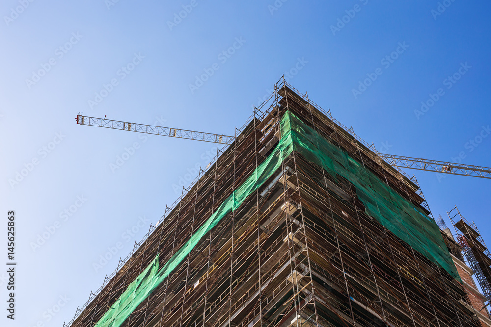 Building crane and building under construction against blue sky Building crane and building under construction against blue sky