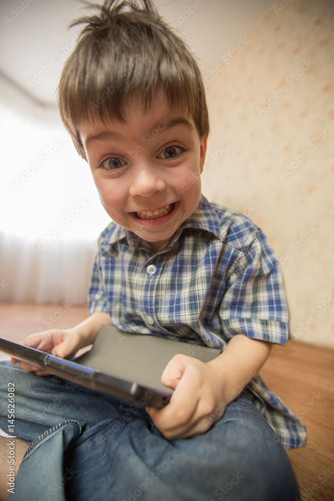 The boy with the tablet was very surprised at what he saw. Strong surprise. Optical distortion of the picture. The boy with the tablet was very surprised at what he saw. Strong surprise. Optical distortion of the picture.
