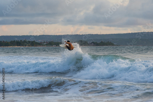 Surfer with a tanned body performs a trick on a short board - a jump over the waves.  photo