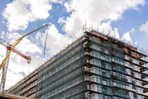 Building crane and building under construction against blue sky