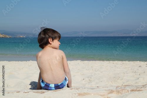 pensive kid looking in the beach