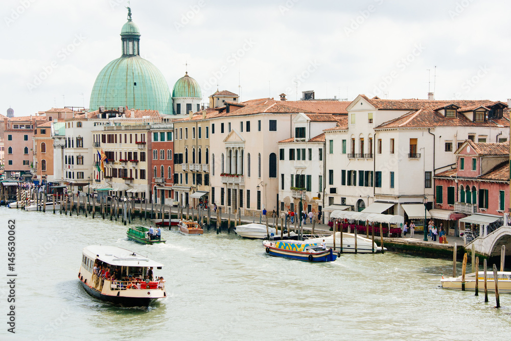 View of the Grand Canal of Venice, Italy. Boat sails on the water with tourists, summer day.
