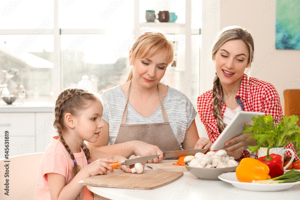 Young woman with mother and daughter cooking in kitchen