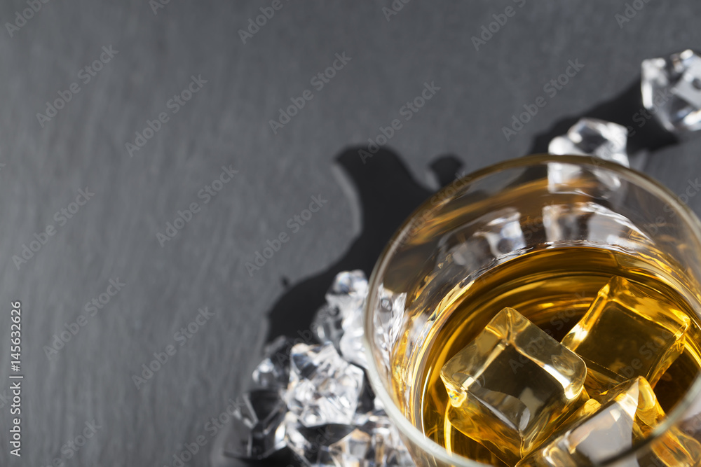 Fragment of glass of whiskey with ice on black background Fragment of glass of whiskey with ice on black background
