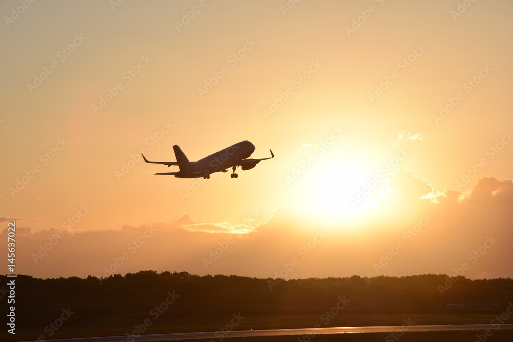 Fototapeta premium Plane taking off with sunset in background
