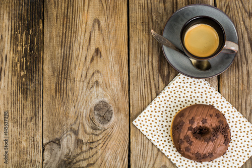 One donut in chocolate glaze on wooden background