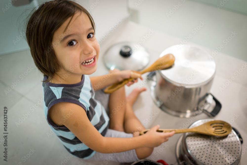 Happy kid at home playing with dishes as music instruments