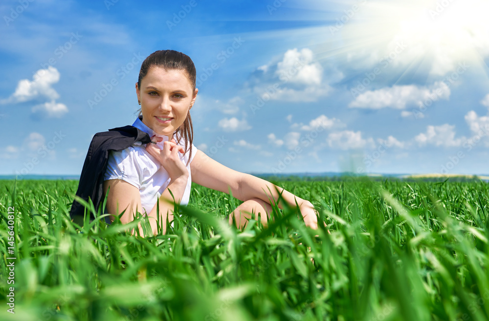 Business woman relaxing in green grass field outdoor under sun. Beautiful young girl dressed in suit resting, spring landscape, bright sunny day Business woman relaxing in green grass field outdoor under sun. Beautiful young girl dressed in suit resting, spring landscape, bright sunny day