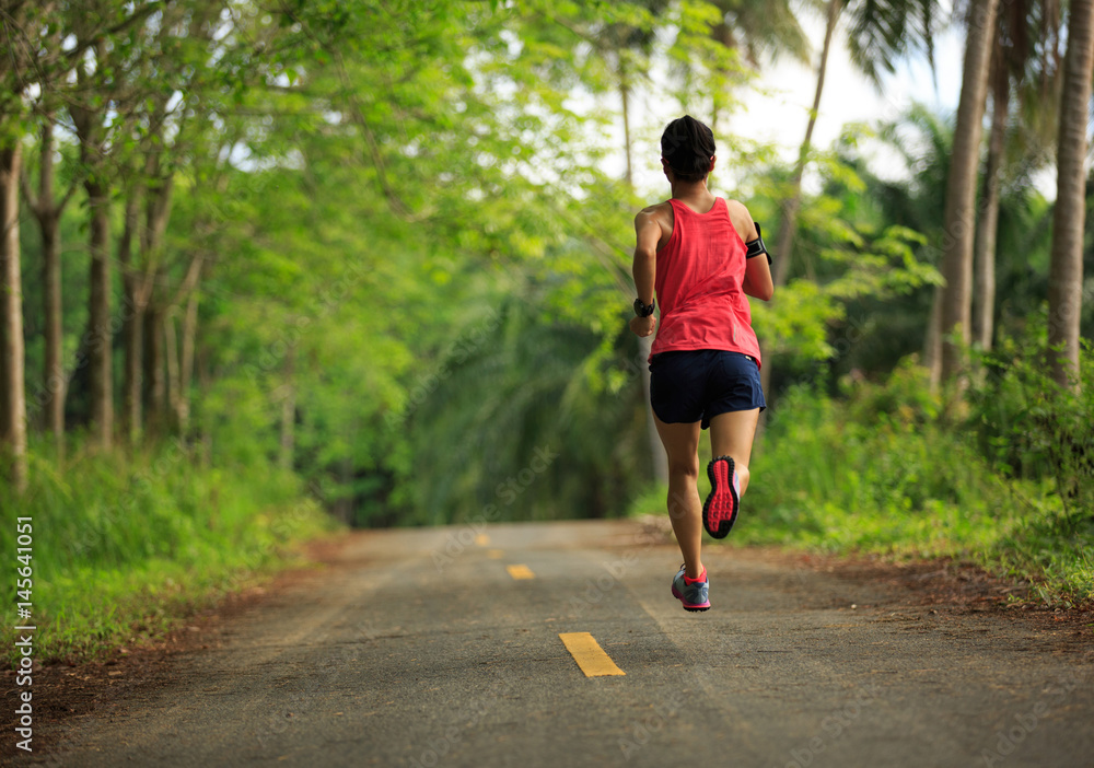 Young fitness woman running on morning tropical forest trail Young fitness woman running on morning tropical forest trail