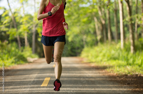 Young fitness woman running on tropical forest trail