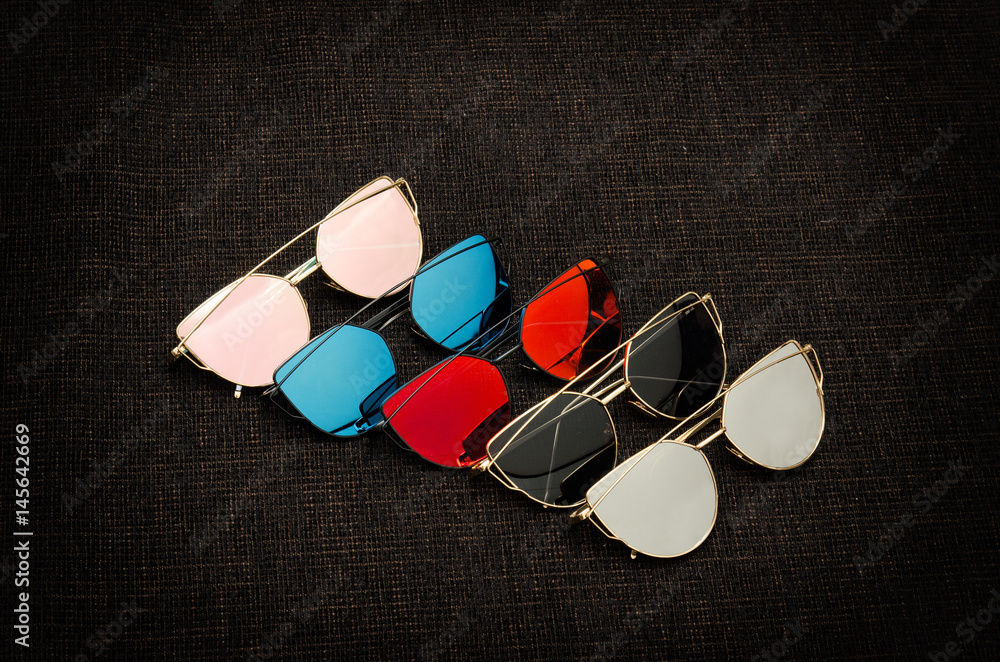 Five sunglasses of different colors on a black background Five sunglasses of different colors on a black background