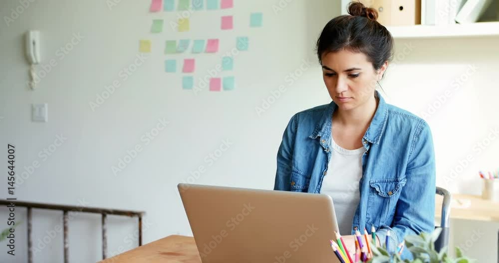 Female executive sitting at desk and using laptop Female executive sitting at desk and using laptop