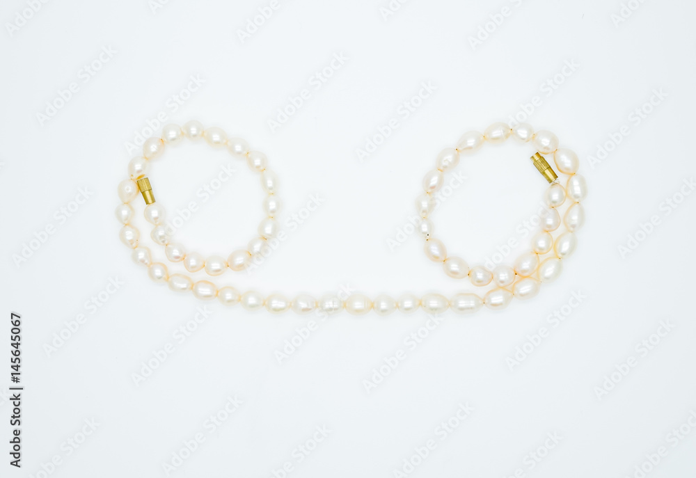 on a white background lies a pink pearl necklace on the neck