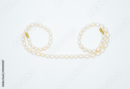 on a white background lies a pink pearl necklace on the neck