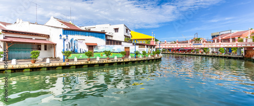 Empty river with small pedestrian bridge during a sunny cloud blue sky in Melaka, a UNESCO World Heritage Site since 7 July 2008. Rustic walkway along the historical river town of Malacca, Malaysia. photo