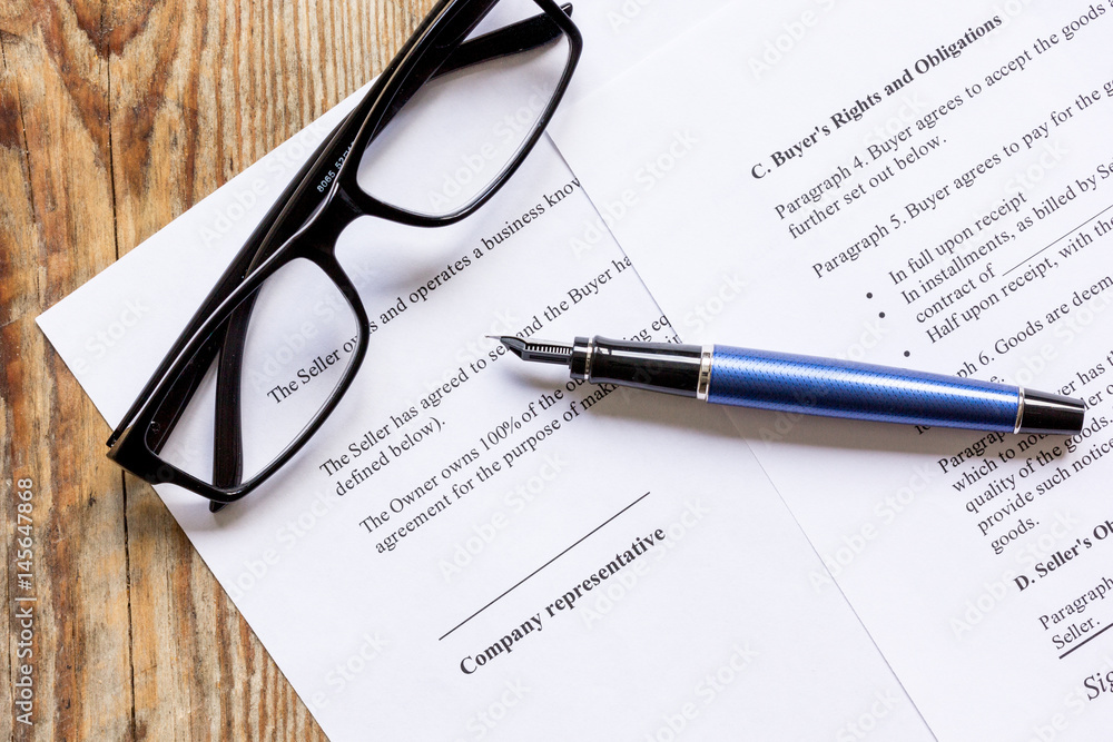 Pen and glasses lying on signed documents on office desk top view Pen and glasses lying on signed documents on office desk top view