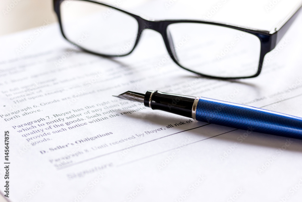 Pen and glasses lying on signed documents on office desk Pen and glasses lying on signed documents on office desk