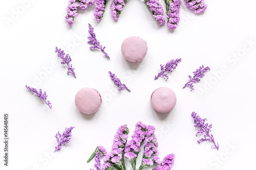 macaroons and flowers for light breakfast on white desk background top view