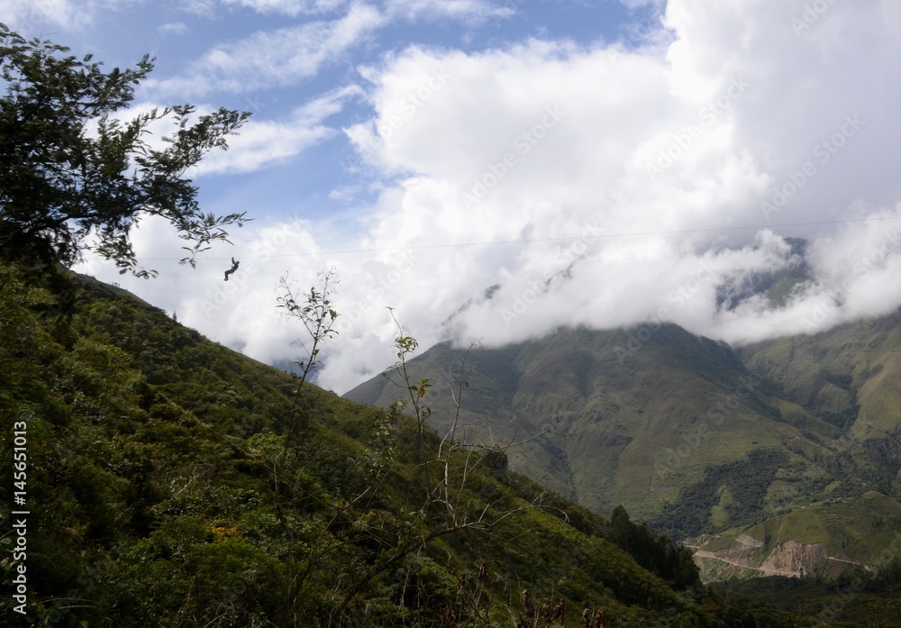 Someone reaching the end of a zip line high above the valley floor in the mountains of Peru.