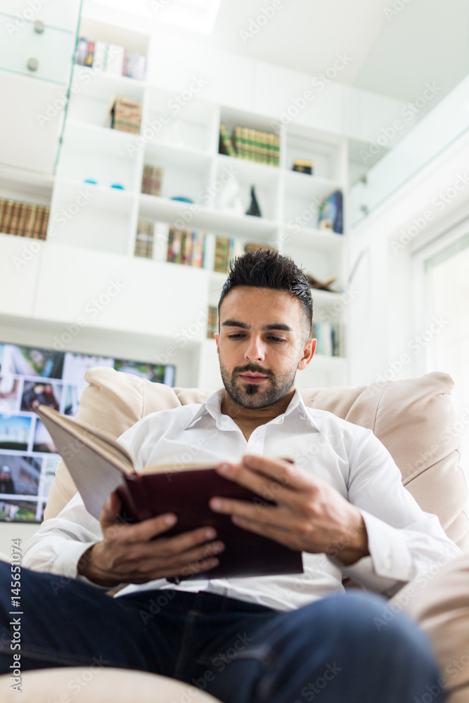 Young confident man reading book at modern home Young confident man reading book at modern home