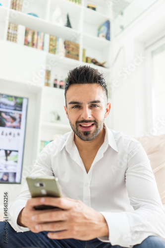 Young good looking man at home using a phone