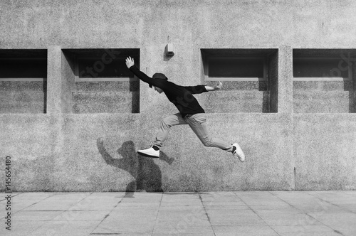 Young man jumping in frount of university campus building photo