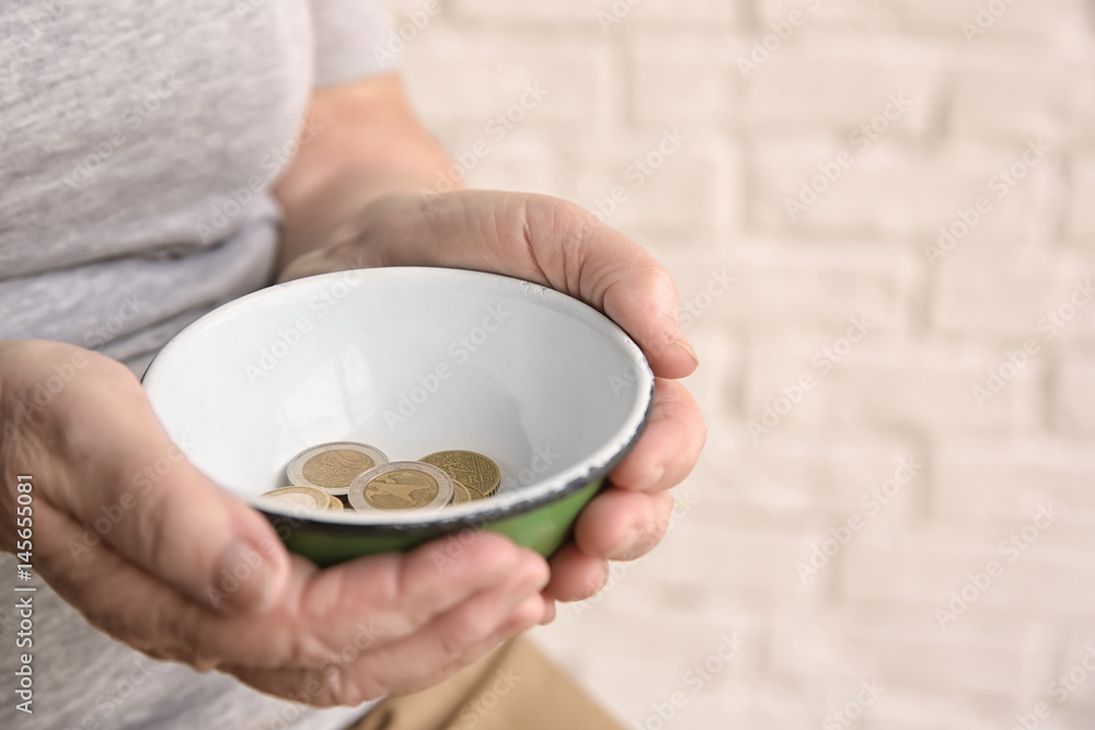 Senior woman with bowl and coins on light background, closeup. Poverty concept Senior woman with bowl and coins on light background, closeup. Poverty concept